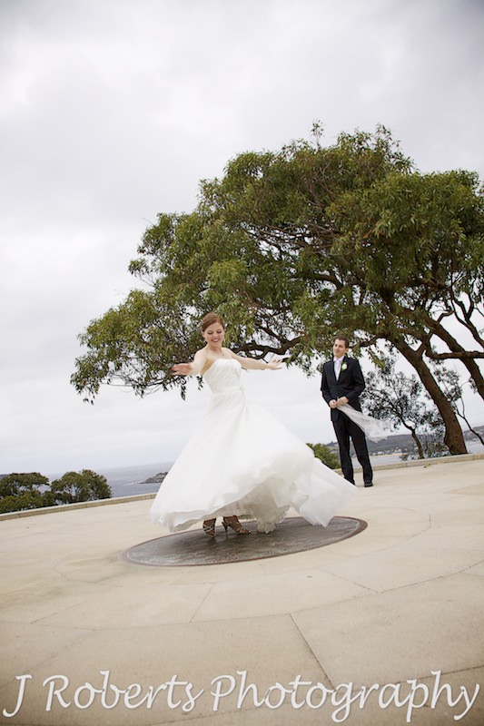 Bride dancing in a swishy skirt with groom looking on - wedding photography sydney